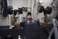 Sailor performs bench presses with dumbbells.