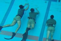 Recon Marines practice breathe-holding techniques at the bottom of a pool.