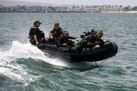Navy SEAL qualification training students ride an inflatable boat.