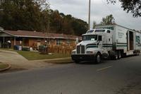 A moving truck is unloaded as a family moves into their new home