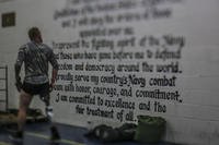 A combat-wounded Marine pauses to look at the Navy Sailor's Creed.