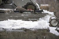 An Ukrainian serviceman peers from an armored personnel carrier