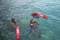 Sailors assist another sailor as he floats in Guam’s Apra Harbor.