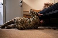 airman inspecting under cot in dorm