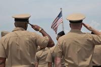 Sailors stand at attention and render honors to the National Ensign.