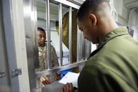 Lance Cpl. Freddie Richardson, disbursing clerk, 15th Marine Expeditionary Unit, assists Sgt. Mohamed R. Muhidin, night crew supervisor, Marine Medium Helicopter Squadron 364, 15th MEU, in setting up his Marine Cash card.