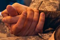 A soldier holds his wife's hand.