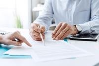 Two people's hands are showing as they look over paperwork.