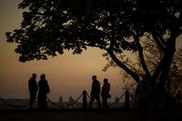 Ukrainian territorial defence forces patrol a public park at sunset.