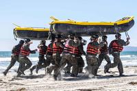 U.S. Navy SEAL candidates run with an inflatable boat on their heads