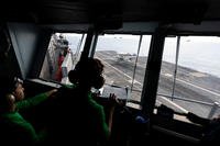 Crew on the primary flight control deck watch as an E-2 Hawkeye lands aboard the USS George Washington