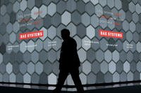 A man walks past a screen in the BAE Systems chalet at the Farnborough Airshow in England.