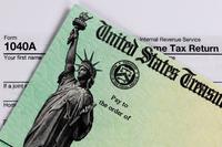 A check from the United States Treasury lies on top of a 1040 tax return form.