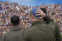 Israeli soldiers look at pictures of revelers killed on Oct. 7, 2023