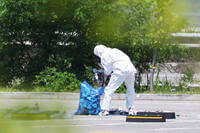 officer wearing protective gear collects the trash from a balloon presumably sent by North Korea