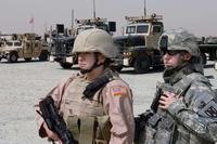 An airman and a soldier stand in front of their trucks at Camp Arifjan, Kuwait