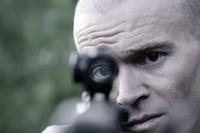 former U.S. Green Beret Jordan Goudreau holds an assault rifle in a documentary film