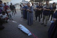 Mourners pray over the body of a Palestinian child