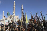Houthi supporters raise their machine guns during a rally