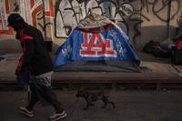 Man walks past a homeless encampment in Los Angeles