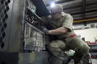 Staff Sgt. Michael Bellanca reaches inside a generator to disconnect a voltage regulator for inspection at Transit Center at Manas, Kyrgyzstan.