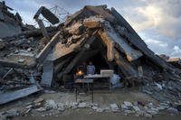 A man sells bread under the destruction of his bakery destroyed by the Israeli air and ground offensive