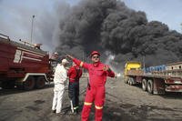 firefighters work as black smoke rises in the sky