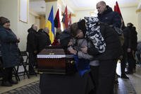 Mother and brother cry at the coffin of Ukrainian soldier.