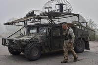 Ukrainian soldier passes by an armoured Hummer vehicle equipped with an anti-drone net
