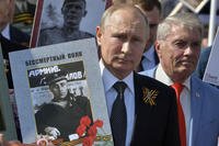 Russian President Vladimir Putin, center, holds a portrait of his father, also named Vladimir