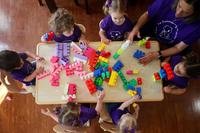 Preschoolers around a low table play with big Legos.