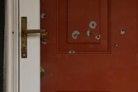 Bullet holes mark the front door of a house.