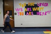 A staff member walks past a message to students that hangs on the wall at Place Bridge Academy