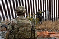 Customs and Border Protection agent places concertina wire along the border