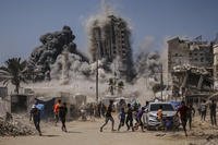 Palestinians run for cover during an Israeli airstrike on a high-rise building in Gaza City