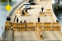 Coast Guardsmen stand watch behind a barrier at Coast Guard Base Alameda.