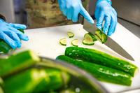 Culinary specialists from the Connecticut Army National Guard cut up cucumbers while preparing a meal inside a containerized kitchen at Fort Drum