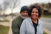 A couple dressed for fall smile for an outdoor portrait.
