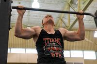A man in a civilian tank top does a pullup.