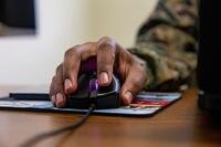 A hand of a uniformed Marine rests on a computer mouse.