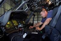 A mechanic looks at controls of an airplane.
