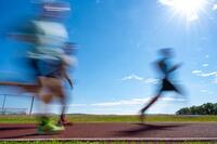 Blurry silhouettes of runners on a track.