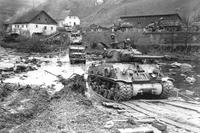 A tank rolls through Normandy shortly after D-Day.