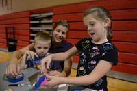 A girl  makes a rocket out of construction paper with her mother and brother during the Child Find Clinic and Community Resource Awareness Fair at Shaw Air Force Base, S.C., Aug. 14, 2013. (Jeffers/Released)