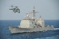 An HH-60H Sea Hawk helicopter assigned to the Sea Knights of Helicopter Sea Combat Squadron (HSC) 22 passes the guided-missile cruiser USS Normandy (CG 60) during a replenishment-at-sea. (Photo by Mass Communication Specialist 3rd Class Anna Van Nuys)