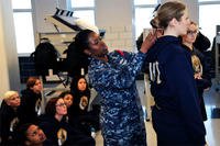 Chief Logistics Specialist Natali Philip, a recruit division commander, uses a ruler to measure the hair of Seaman Recruit Briana Cochems to show proper hair grooming standards to new recruits. (U.S. Navy Photo by Lt. Adam Demeter/Released)