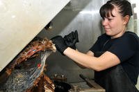 Petty Officer 3rd Class Cassandra Jones scrapes melted plastic waste from a plastics processing compress melt unit on board the aircraft carrier USS Ronald Reagan, March 3, 2011. (U.S. Navy Photo/Petty Officer Nicholas A. Groesch)