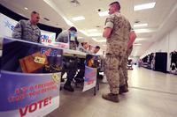 A U.S. Air Force voting officer and a Marine Corps Base assistant voting officer host a joint information booth on Oct. 21,2014, inside the Kadena Exchange, Okinawa, Japan. (USAF Photo: Stephen G. Eigel)