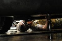 Servicemember on back repairing car.