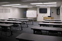 Empty room with desks, a podium and a whiteboard.